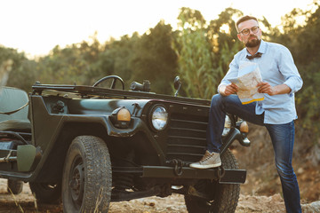 Young stylish man with glasses and bow tie see the map near the