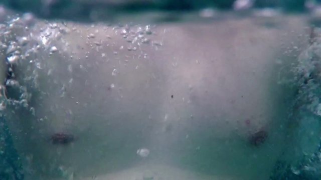We can see a nice man's body in the water. He is standing in the warm whirl pool. The bubbles are everywhere. Close-up shot.
