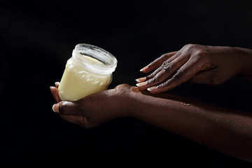 femme noire africaine mettant beurre de karité sur sa peau