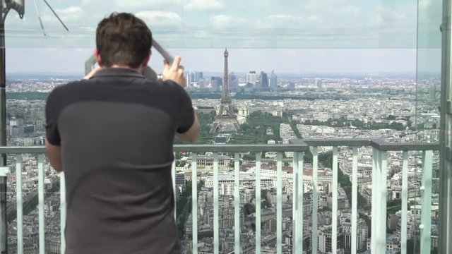 Young Man Watches Eiffel Tower Through Telescope, Paris. The Montparnasse Tower Panoramic Observation Deck has the most beautiful view of Paris