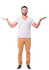 Serious and concentrated latino man with beard spreads his arms. He is trying to compare something. Full length portrait. Isolated on white background.