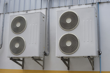 group of air conditioner units on wall outside building.
