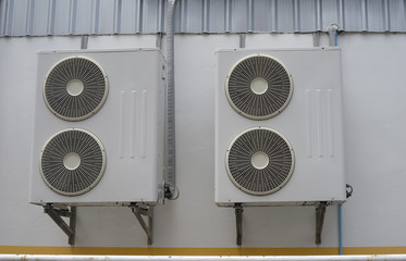 group of air conditioner units on wall outside building.