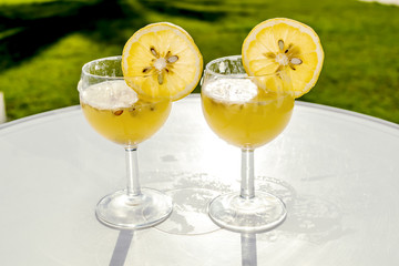 Glasses with juice and slices of lemon are on the table in sunli