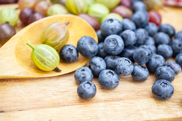 Fresh blueberry and gooseberry on the wooden table - food picture