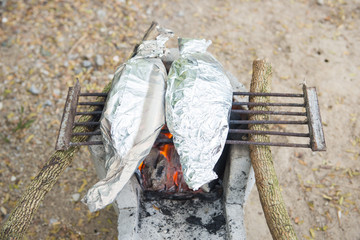 Fresh fish on aluminum foil on charcoal grill