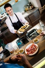 Bartender serving food to customers at counter