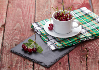 Cherries in the cup on wooden table