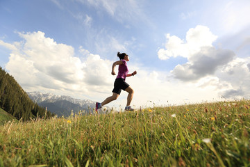 healthy young woman trail runner running on beautiful mountain peak