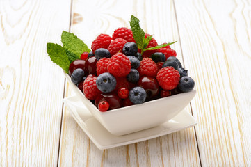 Fresh berries on white wooden table.