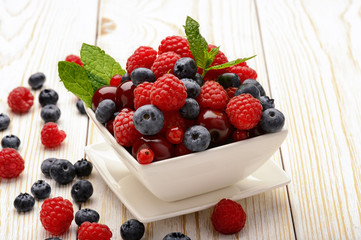 Fresh berries on white wooden table.