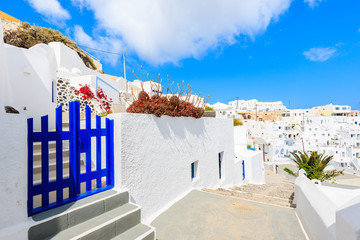 Fototapeta premium Blue gate on narrow street and typical Greek houses in Imerovigli village on Santorini island, Greece