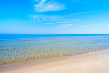 Fototapeta na wymiar Sandy beach with calm azure sea water in Leba, Baltic Sea, Poland