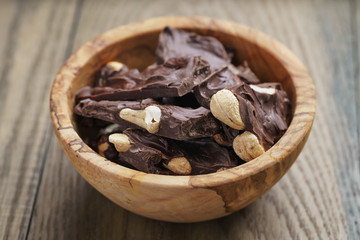 broken homemade bar of chocolate with cashew nuts in wood bowl