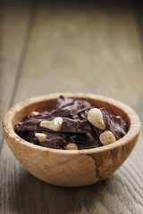 broken homemade bar of chocolate with cashew nuts in wood bowl
