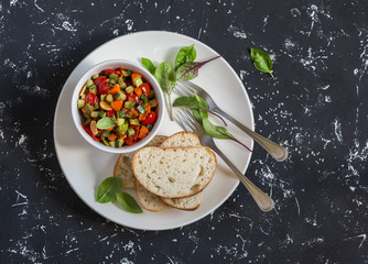 Quick ratatouille and bread on a white plate on a dark background. Delicious healthy vegetarian...
