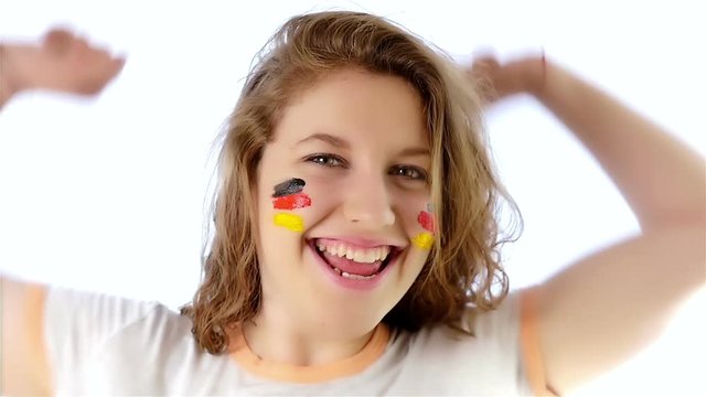 Girl with German flag on her face smiling at the camera, slow motion
