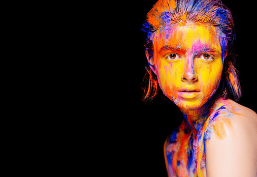 Art makeup. Face, neck and hair girls smeared with bright colors of yellow, blue and pink colors. Holi Festival
