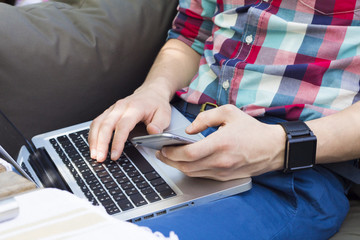 Cropped image of modern man with laptop, phone and watch