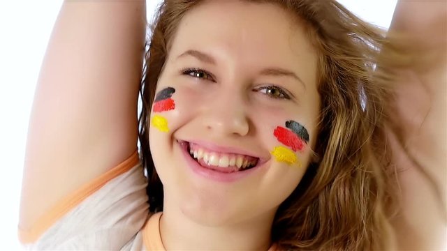 Girl with German flag on her face smiling at the camera, slow motion