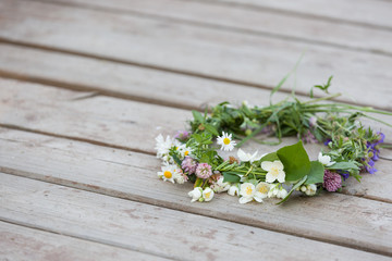 Beautiful summer wreath made on wild flowers on the old wood background. Summer concept