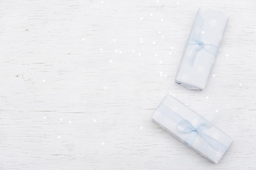 Top view on nicely wrapped gifts in the paper with stars and light blue ribbon on the white wooden background. Presents for birthday, Christmas or any celebration. Holidays concept.
