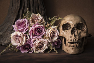 Bouquet purple roses with human skull over tree background on wooden table still life style halloween concept