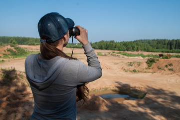 ornithologist girl standing on a cliff with binoculars