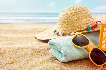 Towel, hat, sunglasses and lotion at ocean beach