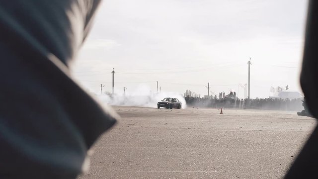 Boys in hood see drifting cars with smoge on the race at a drift competition