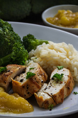 fried chicken breast fillet with broccoli, rice and stewed mango, vertical closeup shot