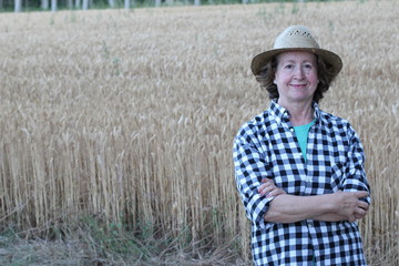 Portrait of mature female farmer smiling on farmland while crossing her arms