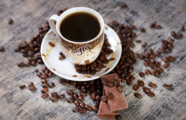 Чашка кофе и шоколад на фоне зернового кофе