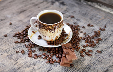 Чашка кофе и шоколад на фоне зернового кофе