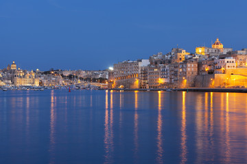 Fototapeta premium Idyllic view of Malta's Tricity area with lights glowing in the sea 