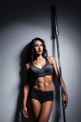studio shot of perfect body of bodybuilder female with barbell;
