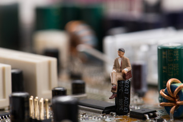 コンピューターの基盤の上で座っているミニチュア人物