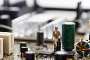 コンピューターの基盤の上で座っているミニチュア人物