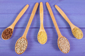 Various groats on wooden spoons, healthy food and nutrition