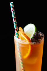 Peach black iced tea consists of vanilla syrup, spices and lemon juice in a glass closeup on dark background