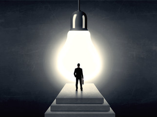 Man standing on a step in front of a huge light bulb