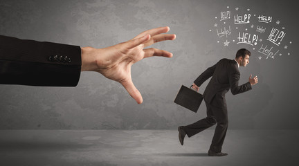 Business person running away from big hand