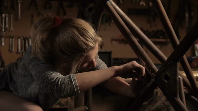 Young woman working as mechanic in garage with tools