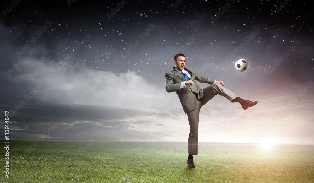 Wall mural Businessman kicking ball . Mixed media