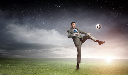 Fototapeta na wymiar Businessman kicking ball . Mixed media