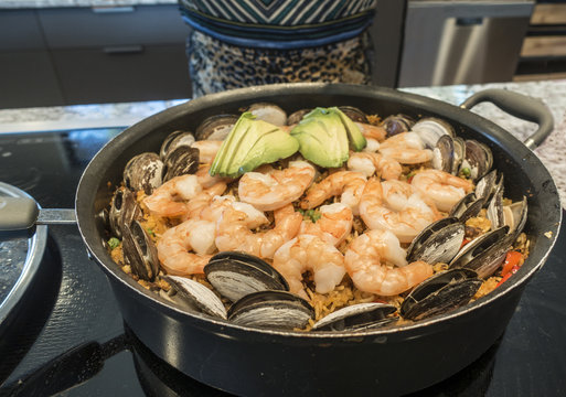 Shrimp Paella in Kitchen Saute Pan On Stove. Ingredients Clams, Avocado, Spanish Rice, Garlic, Paprika, Saffron