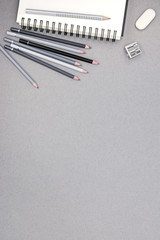 spiral notebook, pencils, eraser, sharpener on gray recycled pap