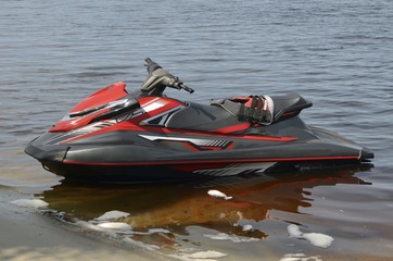 Red and Black Jet Ski Beached in Shallow Water
