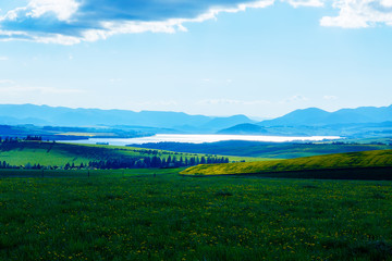 Beautiful landscape, green and yellow meadow and lake with mountain in background. Slovakia, Central Europe.