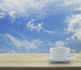 White coffee cup on wooden table and blue sky